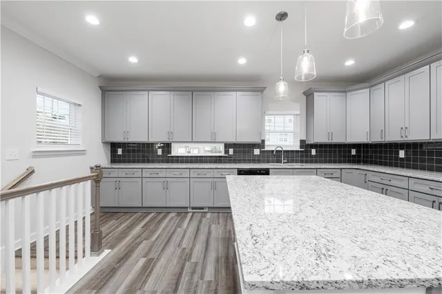 a large kitchen with granite countertop a stove and white cabinets