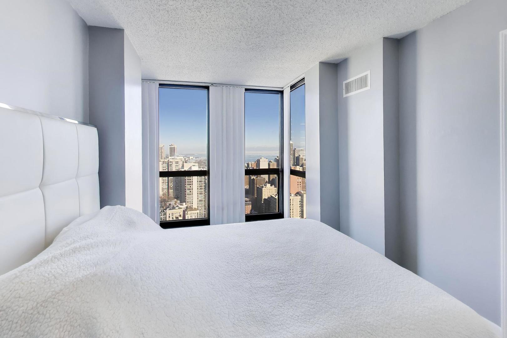 1122 North Clark Street, Unit 3705 Chicago, IL 60610 - Photo 15 of 38 a large bedroom with bed and mirror