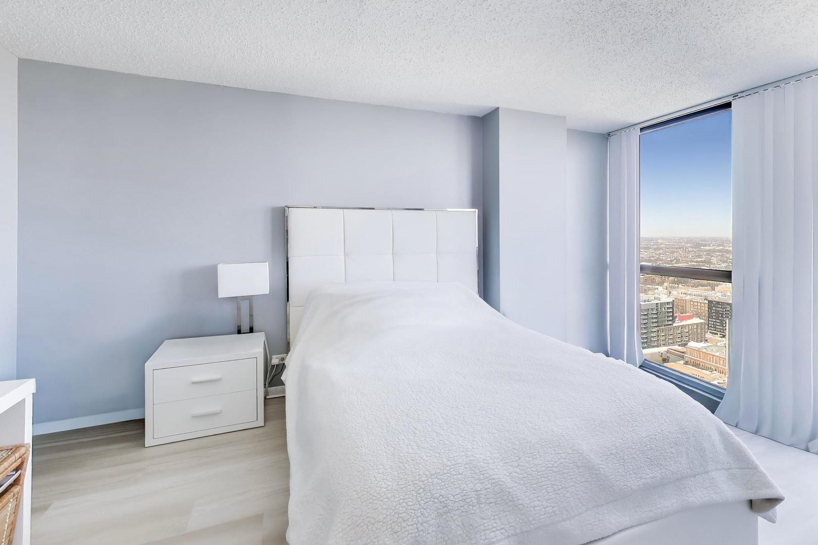 1122 North Clark Street, Unit 3705 Chicago, IL 60610 - Photo 18 of 38 a bedroom with a white bed and a large window