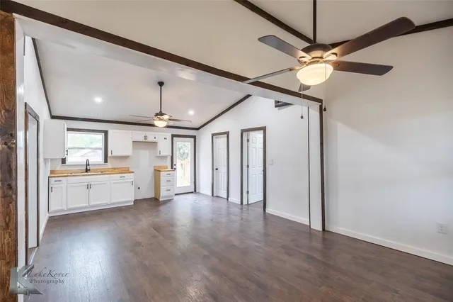 a large space with chandelier fan and wooden floor