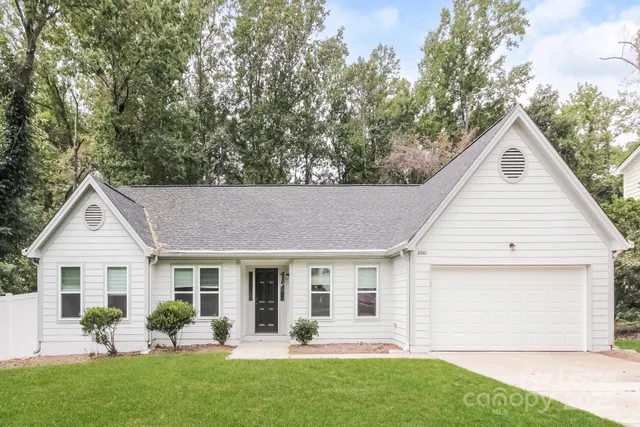 a view of a white house with a yard and sitting area