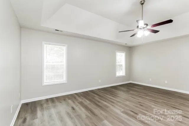 a view of an empty room with window and chandelier fan
