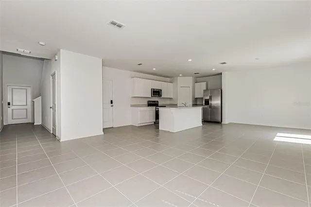 a view of a kitchen with refrigerator and white cabinets
