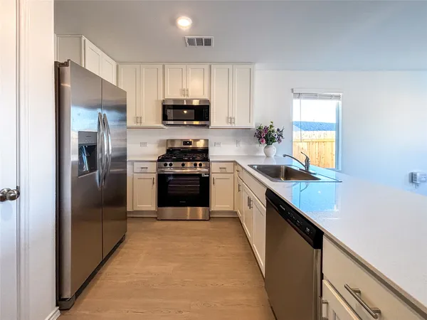 a large kitchen with stainless steel appliances granite countertop a stove a sink and a refrigerator