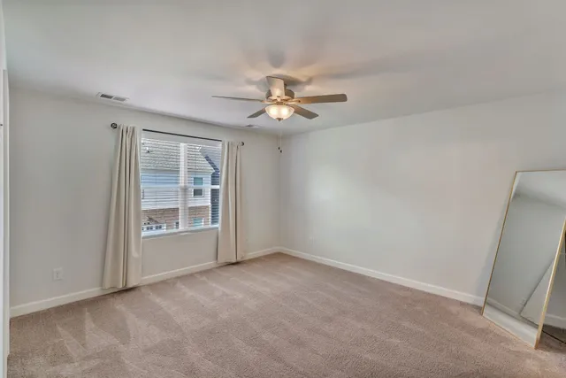 an empty room with windows and fan
