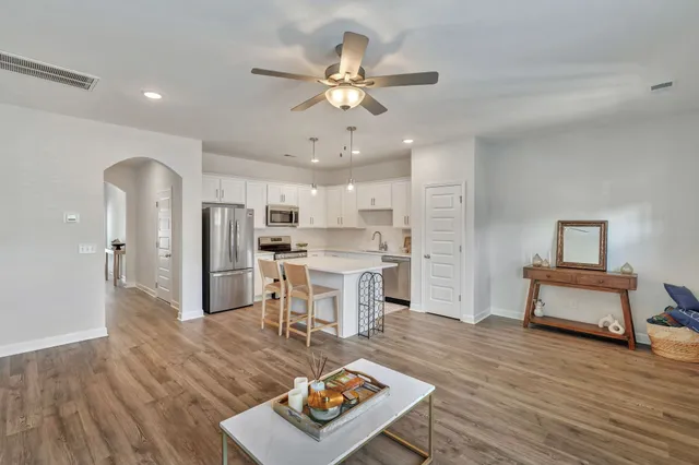 a living room with furniture and kitchen view with wooden floor