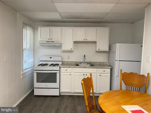 a kitchen with stainless steel appliances granite countertop a stove a refrigerator a stove a sink dishwasher and white cabinets with wooden floor