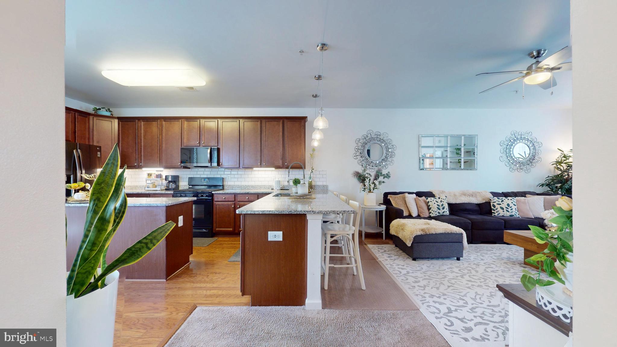 8548 Golden Eagle Lane Severn, MD 21144 - Photo 11 of 76 a kitchen with stainless steel appliances kitchen island granite countertop a refrigerator a sink dishwasher a dining table and chairs with wooden floor