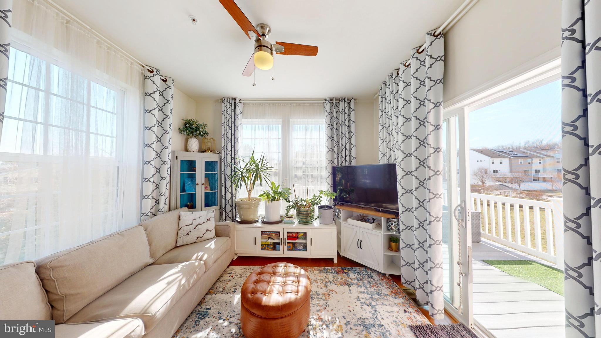8548 Golden Eagle Lane Severn, MD 21144 - Photo 26 of 76 a living room with furniture a flat screen tv and a floor to ceiling window