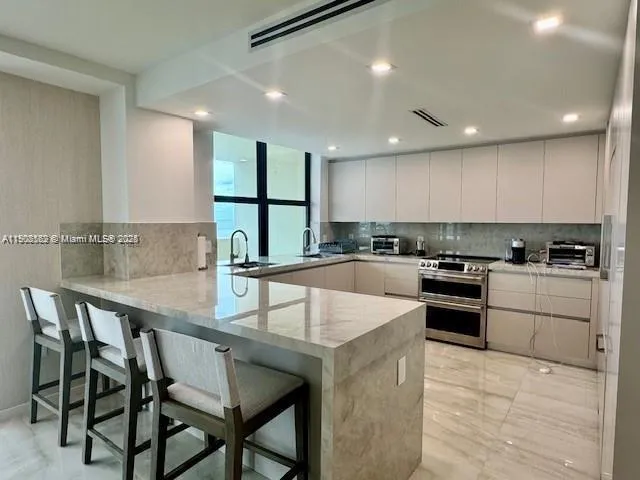 a kitchen with stainless steel appliances granite countertop a table chairs sink and cabinets