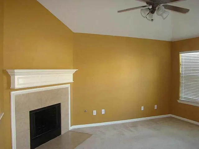 a view of an empty room with a fireplace and windows