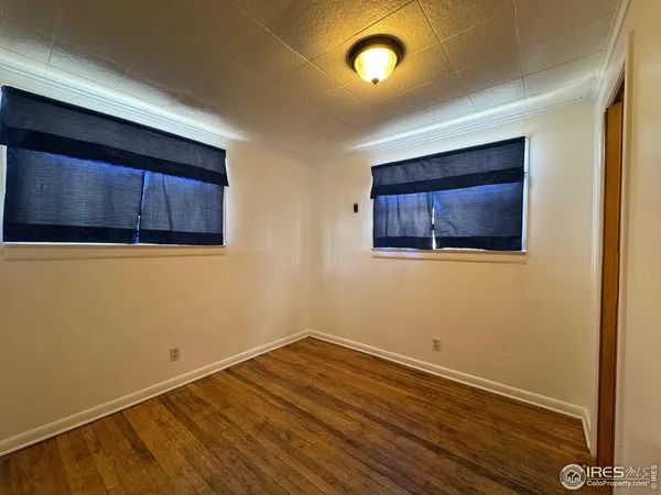 a view of an empty room with wooden floor and a cabinet