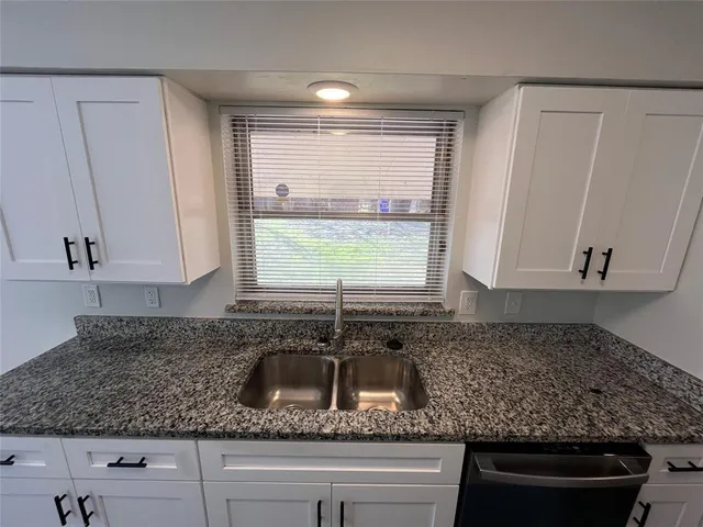 a kitchen with sink a window and cabinets