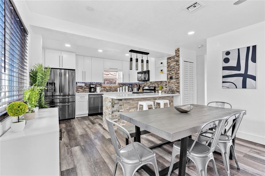 7831 Hope Street Hollywood, FL 33024 - Photo 6 of 19 a kitchen with a table chairs refrigerator and microwave