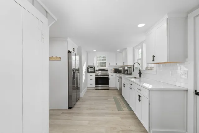 a large kitchen with a white stove top oven cabinets and stainless steel appliances