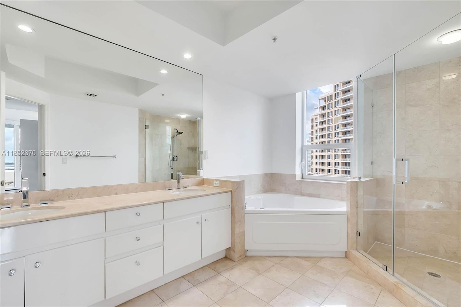 848 Brickell Key Drive, Unit 1906 Miami, FL 33131 - Photo 18 of 24 a bathroom with a double vanity sink a large mirror and shower