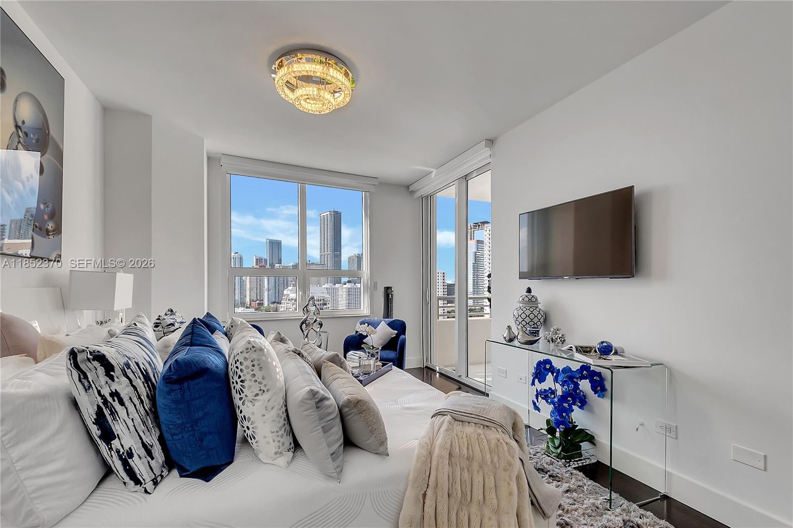 848 Brickell Key Drive, Unit 1906 Miami, FL 33131 - Photo 20 of 24 a living room with furniture a flat screen tv and a floor to ceiling window