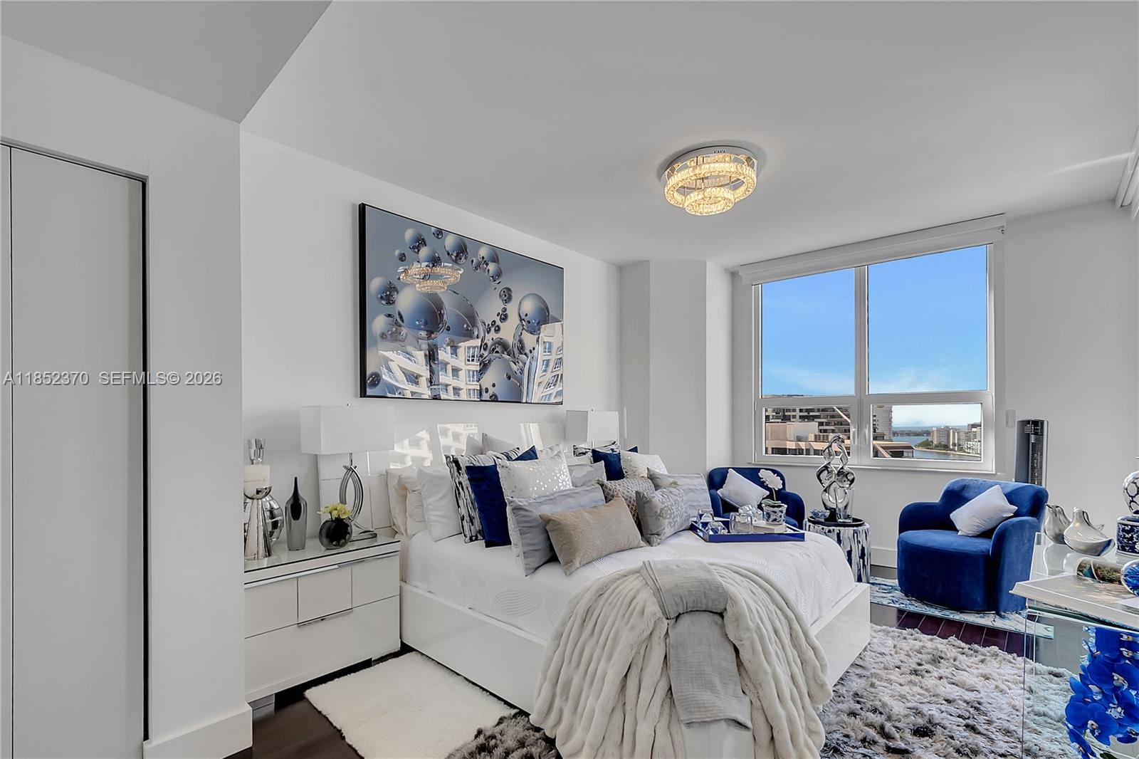 848 Brickell Key Drive, Unit 1906 Miami, FL 33131 - Photo 21 of 24 a living room with furniture a chandelier and a window