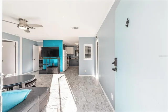 a living room with a fireplace furniture a ceiling fan and a window