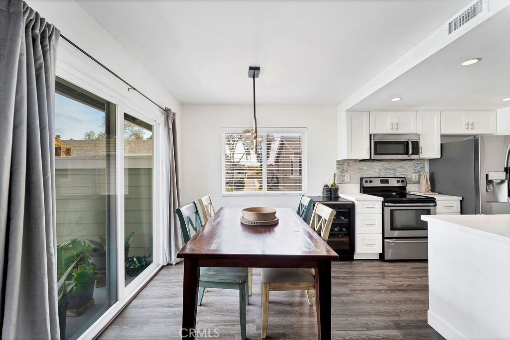 4267 Arcata Bay Way Oceanside, CA 92058 - Photo 23 of 34 a kitchen with stainless steel appliances granite countertop a stove top oven a sink dishwasher a dining table and chairs with wooden floor