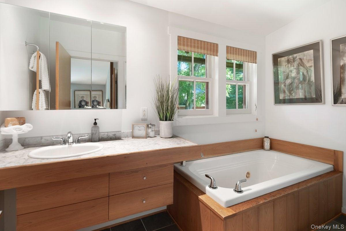 1821 Spring Valley Road Ossining, NY 10562 - Photo 31 of 48 The primary bath offers a true spa experience with a jacuzzi soaking tub. A separate stand-up shower, floating vanity, and large windows enhance the space.