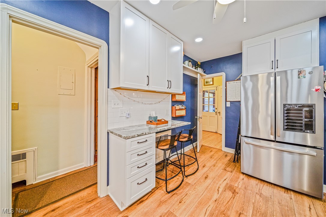 2710 Edgehill Road Cleveland, OH 44106 - Photo 16 of 44 Kitchen with stainless steel fridge with ice dispenser, light stone counters, light wood-type flooring, and white cabinetry