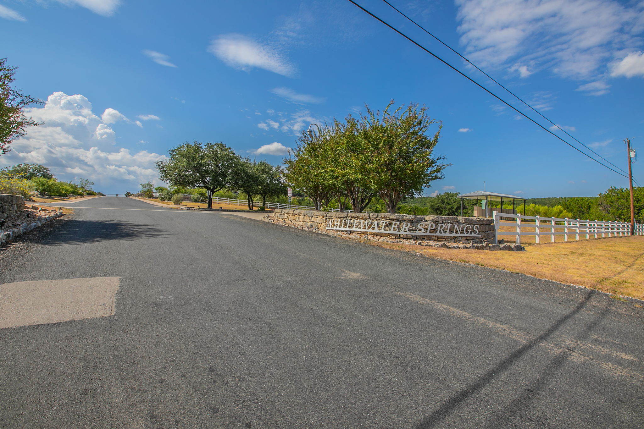 76 Balcones Ridge Way Bertram, TX 78605 - Photo 12 of 16 An inviting entrance road leads past a stone retaining wall under wide open skies.