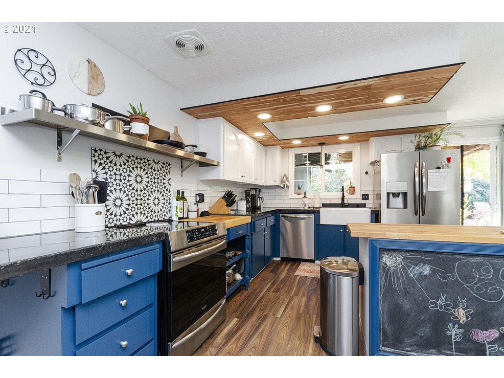 290 Southeast Palmblad Drive Gresham, OR 97080 - Photo 11 of 32 a kitchen with stainless steel appliances kitchen island granite countertop a table chairs in it and wooden floors