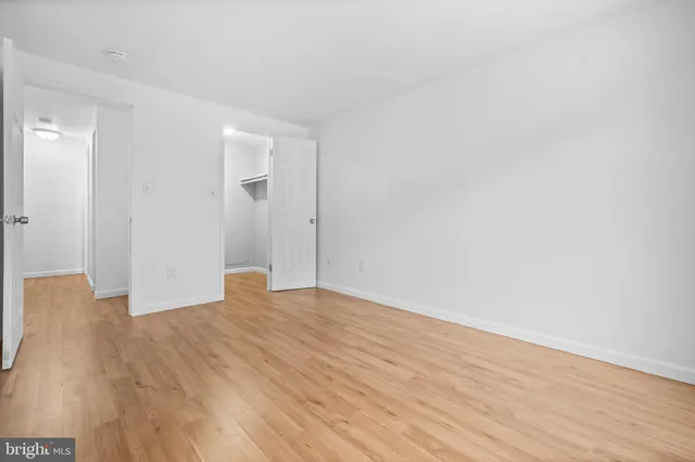 a view of an empty room with wooden floor and a ceiling fan