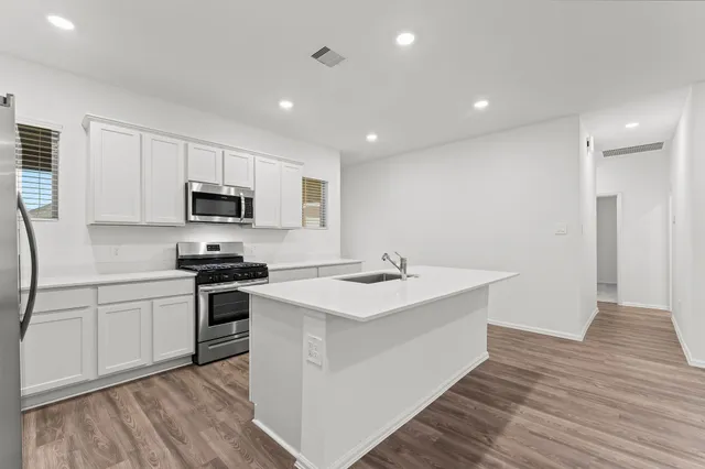 a view of kitchen with kitchen island a sink wooden floor and white cabinets