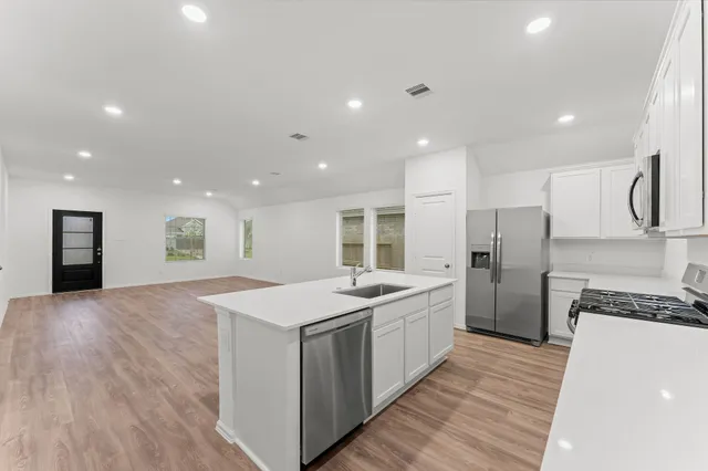 a large kitchen with stainless steel appliances a large counter top a stove and a refrigerator