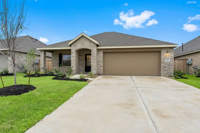 a view of a yard in front of a house with plants and large tree