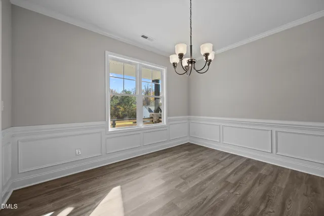 a view of empty room with wooden floor and window