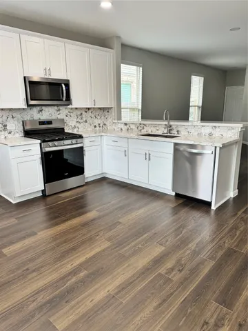 a kitchen with stainless steel appliances a white stove top oven and white cabinets