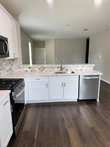 a kitchen with stainless steel appliances white cabinets a sink and wooden floor