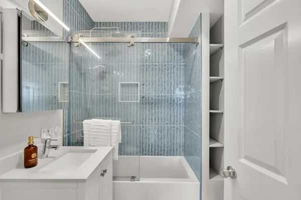 a bathroom with a tub shower vanity and a sink