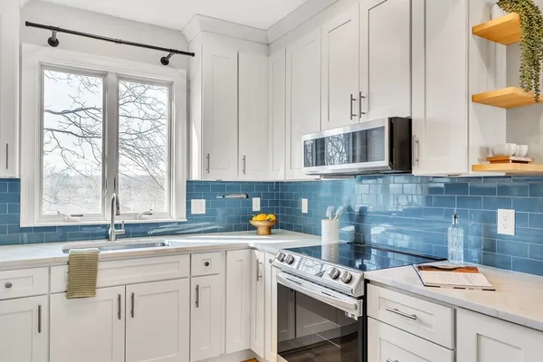 a kitchen with stainless steel appliances white cabinets sink and a window