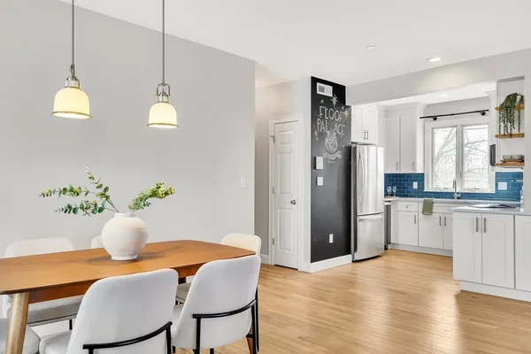 a kitchen with stainless steel appliances granite countertop a refrigerator a sink dishwasher a dining table and chairs with wooden floor