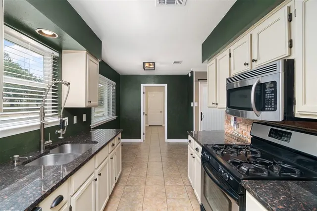 a kitchen with stainless steel appliances granite countertop a stove a sink and a microwave