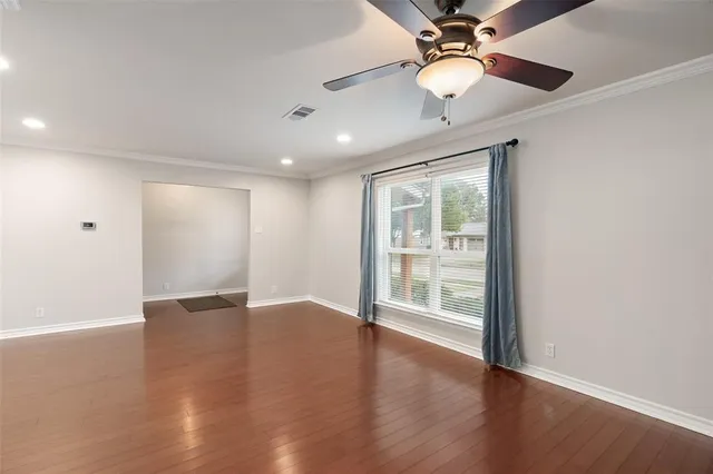 a view of an empty room with wooden floor and a window