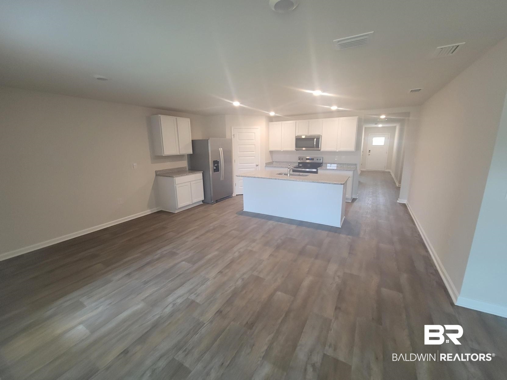 24625 Ponder Loop Loxley, AL 36551 - Photo 23 of 30 Kitchen with white cabinets, hardwood / wood-style floors, stainless steel appliances, and a kitchen island with sink