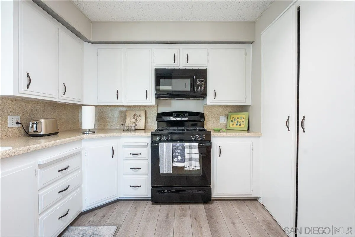90 Blue Sky Lane Oceanside, CA 92056 - Photo 13 of 26 a kitchen with white cabinets a sink and wooden floor