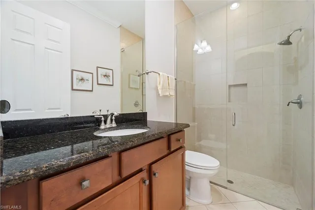 a bathroom with a granite countertop sink a toilet a mirror and shower