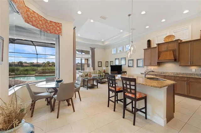 a very nice looking open dining room with kitchen island granite countertop a table chairs and a view of living room