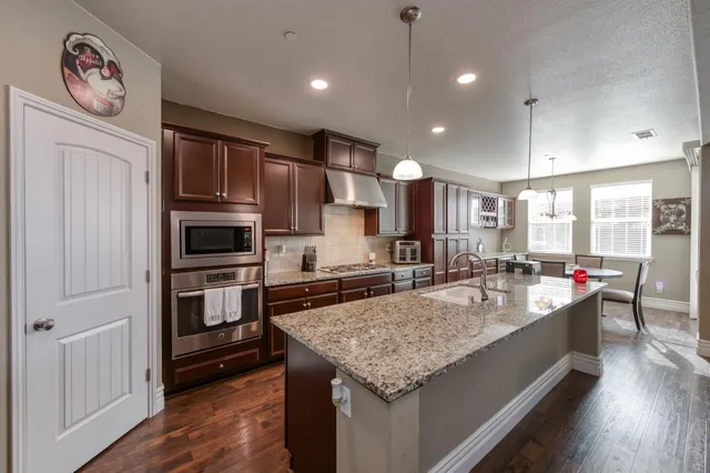 a kitchen with stainless steel appliances granite countertop a sink refrigerator and cabinets