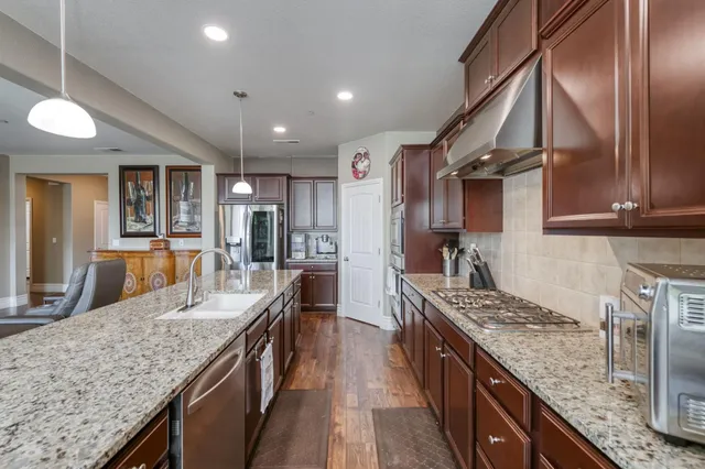a kitchen with stainless steel appliances granite countertop sink stove top oven and refrigerator