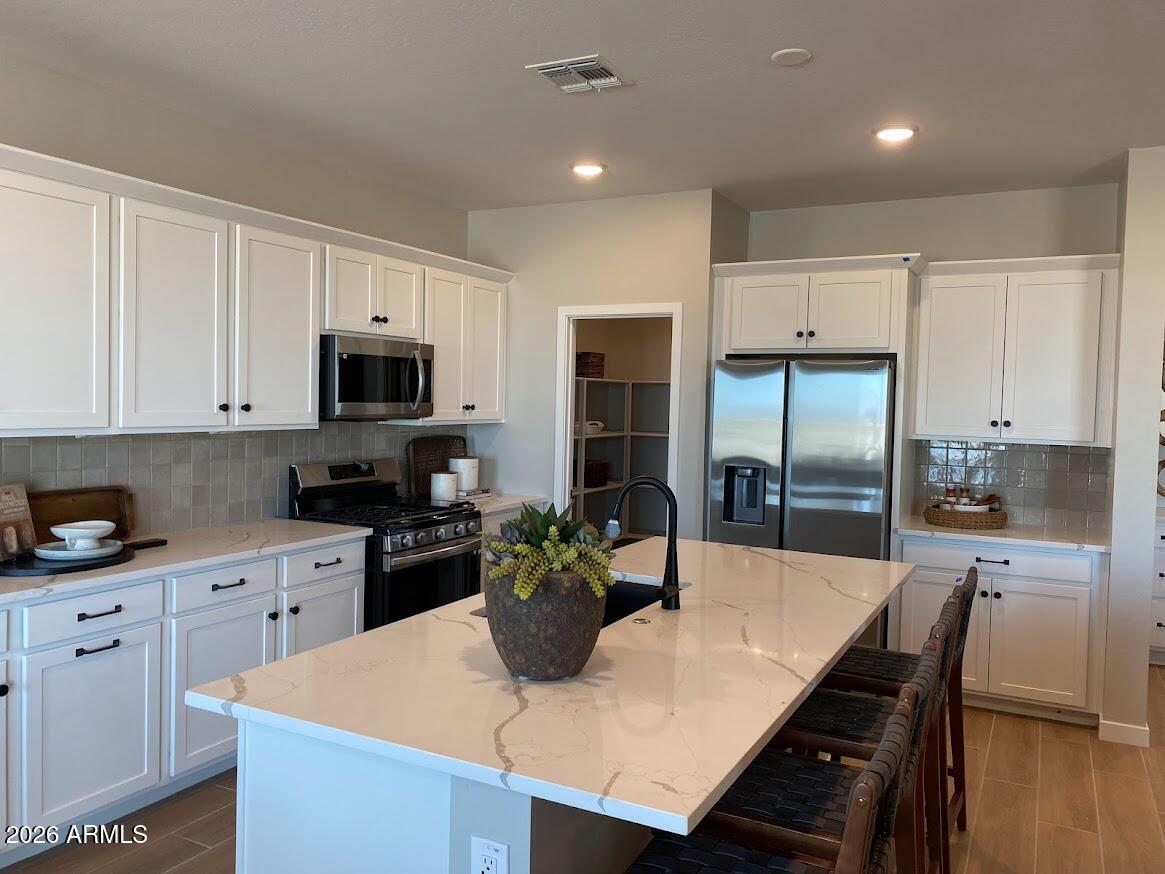 17547 West Fulton Street Goodyear, AZ 85338 - Photo 2 of 10 a kitchen with kitchen island a refrigerator stove microwave and cabinets
