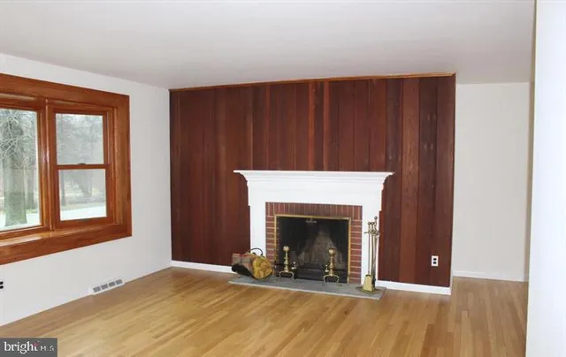 a view of an empty room with wooden floor and a fireplace