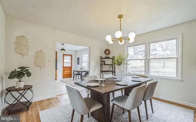 a dining room with wooden floor a chandelier a wooden table and chairs