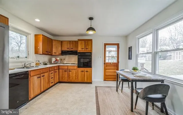 a kitchen with stainless steel appliances granite countertop a stove top oven a sink dishwasher a dining table and chairs with wooden floor